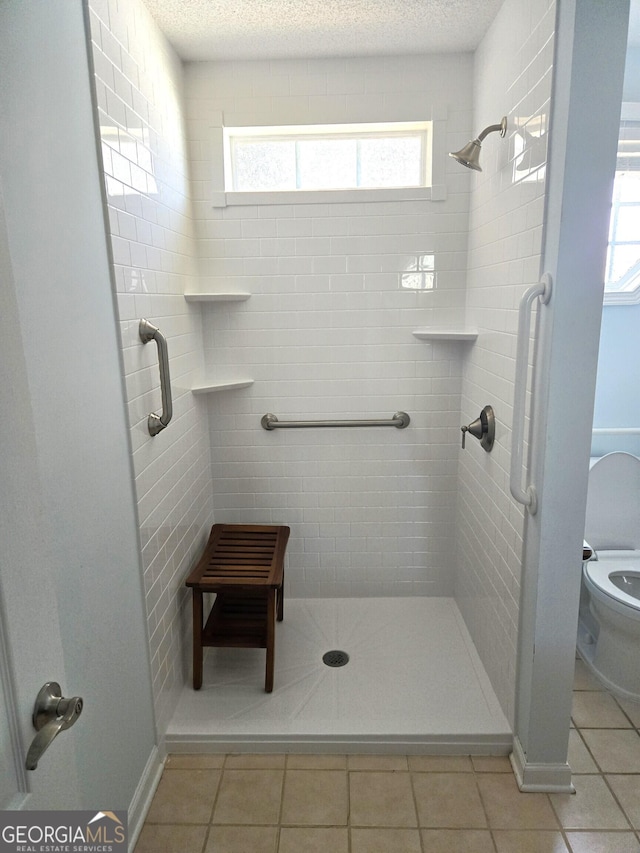 full bath featuring tile patterned flooring, a textured ceiling, and a shower stall