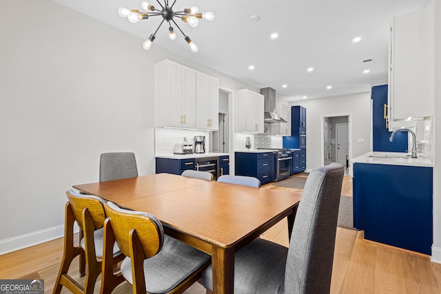 dining space featuring sink, beverage cooler, a chandelier, and light wood-type flooring