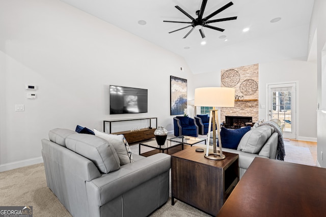 carpeted living room featuring high vaulted ceiling, a stone fireplace, and ceiling fan