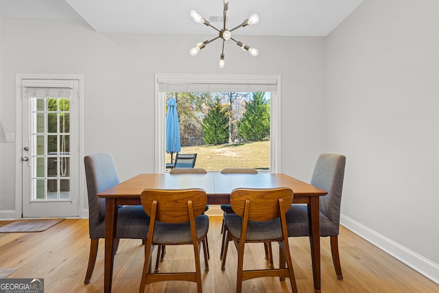 dining space with light hardwood / wood-style flooring, plenty of natural light, and a notable chandelier