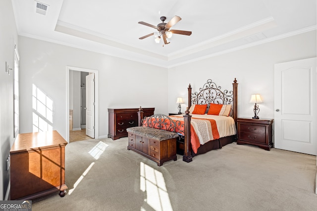 bedroom with ceiling fan, ornamental molding, light carpet, and a tray ceiling