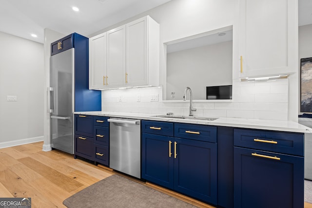 kitchen with blue cabinetry, white cabinets, sink, and appliances with stainless steel finishes