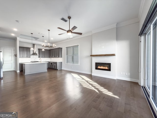 unfurnished living room featuring ornamental molding, dark wood-type flooring, a glass covered fireplace, and visible vents