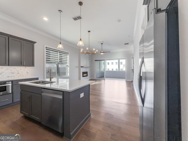 kitchen featuring an island with sink, appliances with stainless steel finishes, light countertops, and a sink