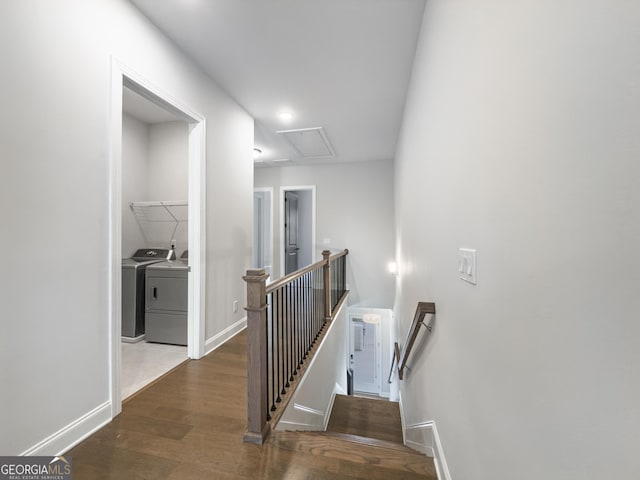 corridor with dark wood finished floors, washer and clothes dryer, attic access, an upstairs landing, and baseboards