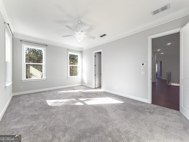 empty room featuring visible vents, crown molding, and carpet flooring