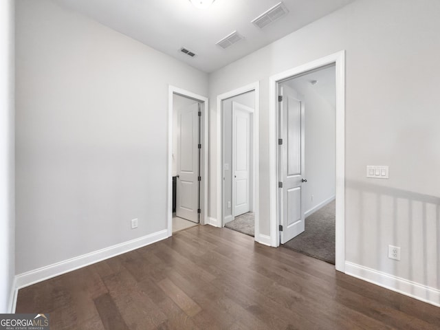 empty room featuring baseboards, visible vents, and dark wood finished floors