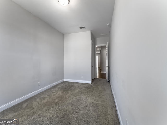 unfurnished bedroom with visible vents, dark carpet, and baseboards