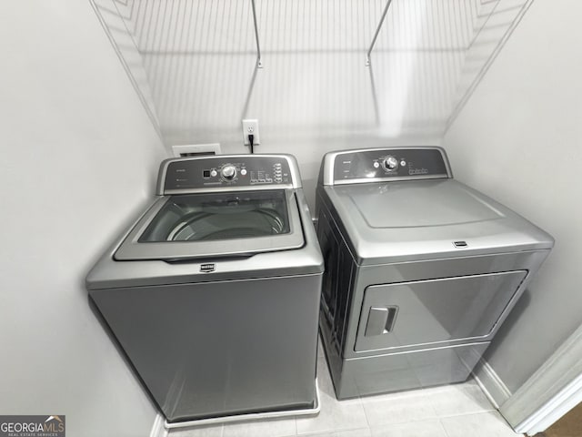 clothes washing area featuring laundry area, washer and dryer, and light tile patterned flooring