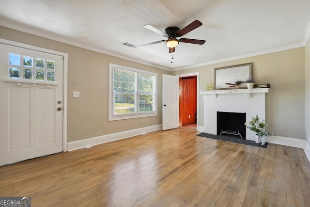 unfurnished living room with hardwood / wood-style flooring, a brick fireplace, plenty of natural light, and crown molding