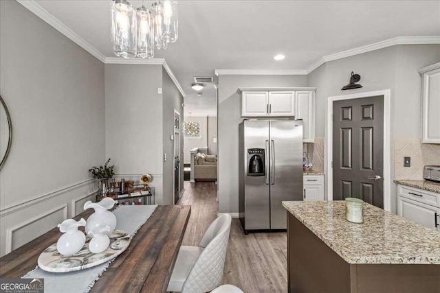 kitchen featuring pendant lighting, white cabinets, stainless steel fridge, ornamental molding, and wood-type flooring