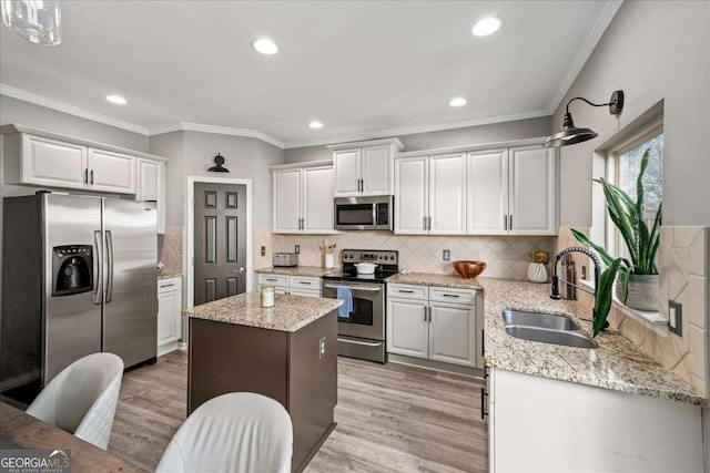 kitchen with a center island, sink, light hardwood / wood-style floors, white cabinetry, and stainless steel appliances