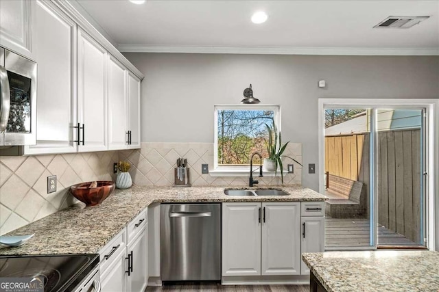 kitchen with a wealth of natural light, white cabinetry, sink, and stainless steel appliances