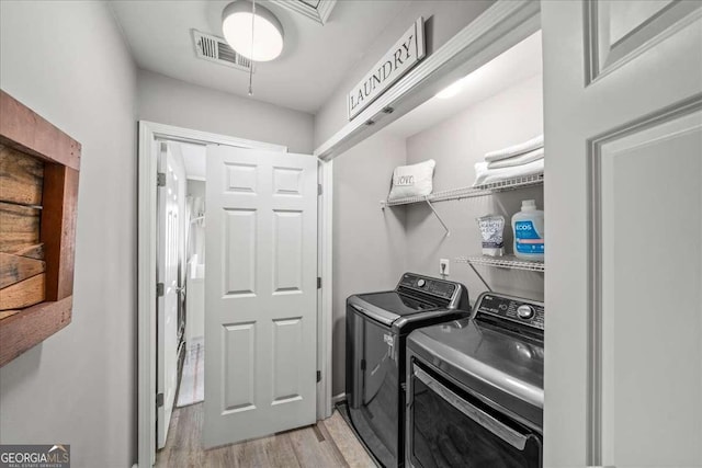 laundry room with light hardwood / wood-style floors and washer and clothes dryer