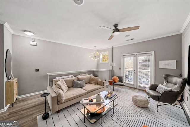 living room featuring hardwood / wood-style floors, ceiling fan with notable chandelier, french doors, and crown molding