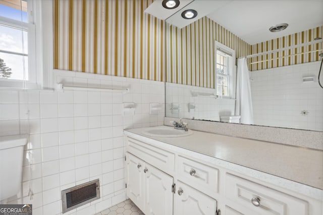 bathroom with tile patterned flooring, vanity, toilet, and tile walls