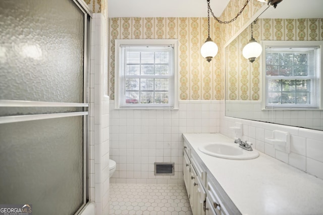 bathroom with tile patterned flooring, vanity, a shower with door, and tile walls