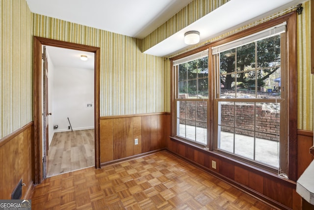 unfurnished room with light parquet floors and wood walls