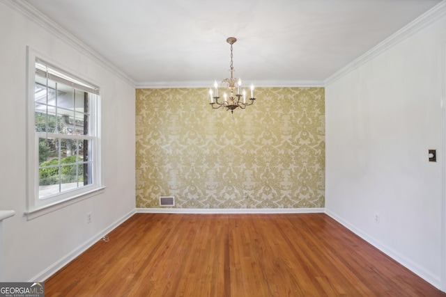 spare room with hardwood / wood-style floors, ornamental molding, and a chandelier