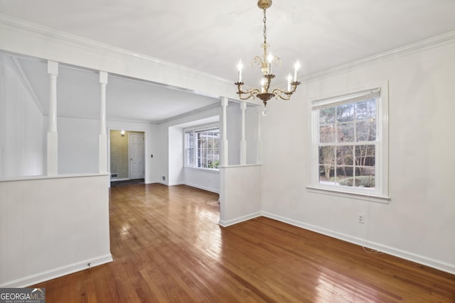 unfurnished dining area featuring a notable chandelier, a healthy amount of sunlight, ornamental molding, and dark wood-type flooring