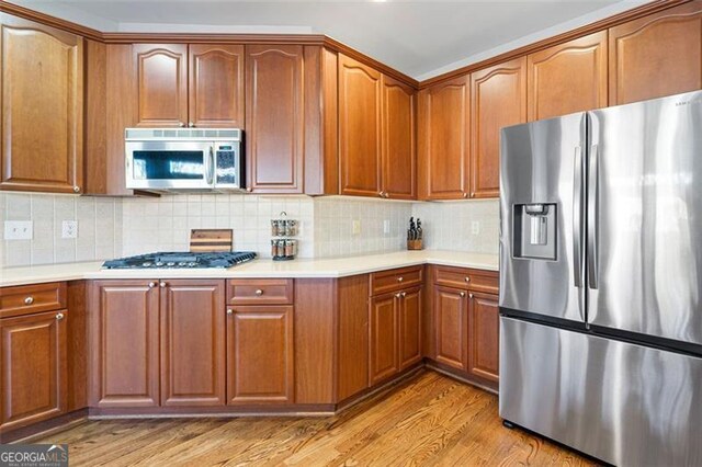 kitchen featuring decorative backsplash, stainless steel appliances, and light wood-type flooring