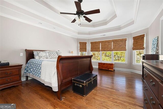 bedroom featuring a tray ceiling, ceiling fan, wood-type flooring, and ornamental molding