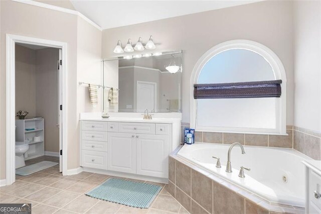 bathroom featuring vanity, tile patterned floors, crown molding, toilet, and tiled tub