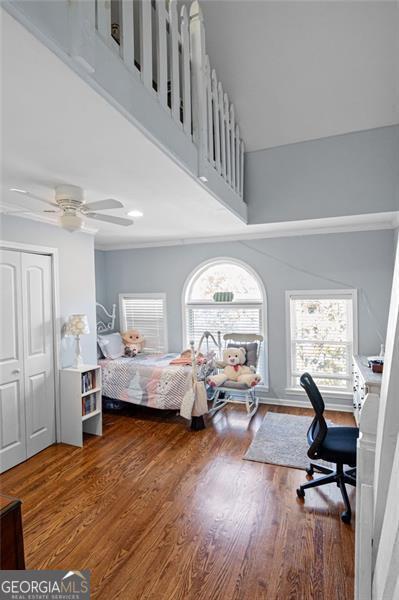 bedroom featuring ceiling fan, a closet, dark hardwood / wood-style flooring, and multiple windows