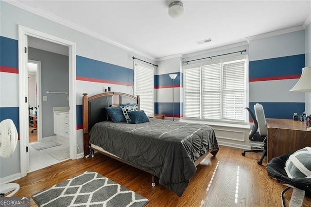 bedroom with hardwood / wood-style floors, ensuite bathroom, and ornamental molding