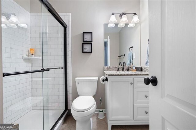 bathroom featuring vanity, toilet, and an enclosed shower