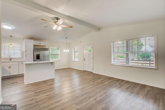 unfurnished living room with vaulted ceiling with beams, light hardwood / wood-style flooring, ceiling fan, and sink