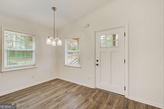 foyer with crown molding, a healthy amount of sunlight, vaulted ceiling, and hardwood / wood-style flooring