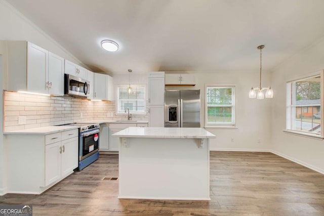 kitchen with a healthy amount of sunlight, white cabinetry, a center island, and stainless steel appliances