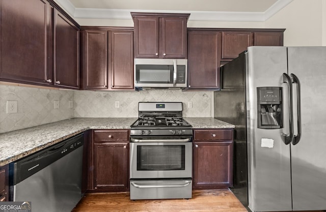 kitchen with backsplash, dark brown cabinetry, light wood-type flooring, ornamental molding, and appliances with stainless steel finishes