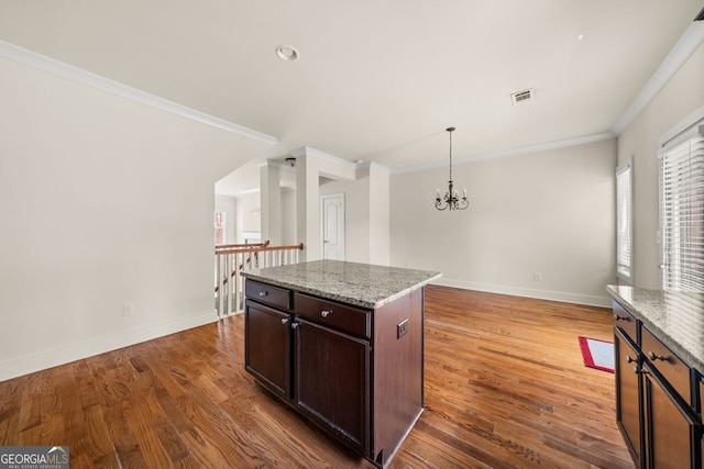 kitchen with crown molding, wood finished floors, visible vents, and baseboards