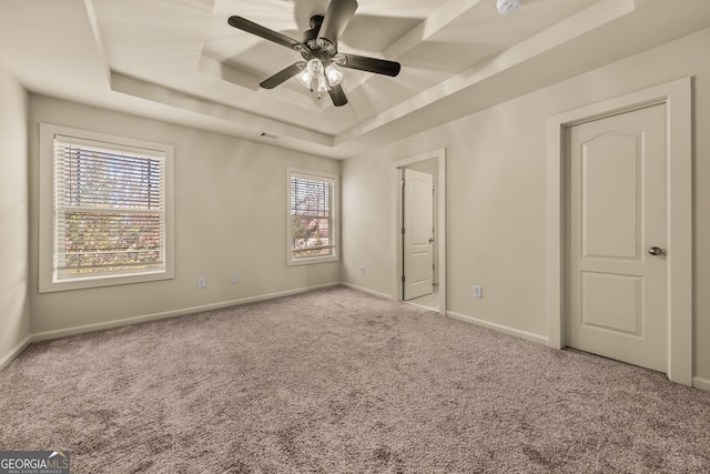 unfurnished bedroom featuring visible vents, a raised ceiling, a ceiling fan, carpet flooring, and baseboards