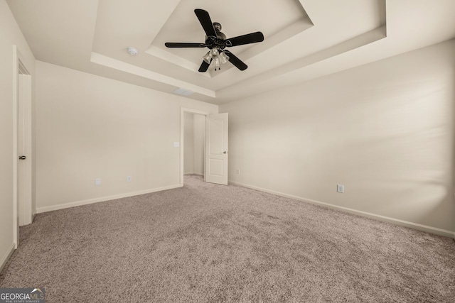 unfurnished bedroom with baseboards, carpet, a tray ceiling, and a ceiling fan