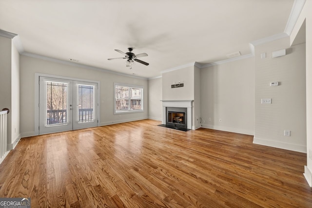 unfurnished living room featuring ornamental molding, baseboards, ceiling fan, and wood finished floors