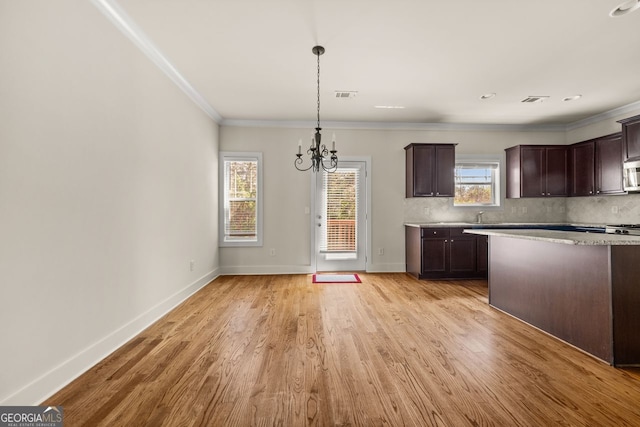 kitchen with visible vents, dark brown cabinetry, decorative backsplash, light wood-style floors, and an inviting chandelier