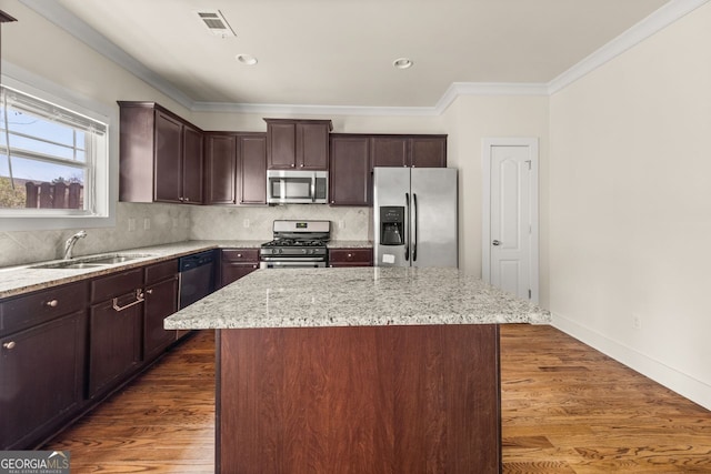 kitchen with a sink, stainless steel appliances, backsplash, and a center island