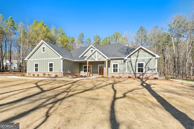 view of front of house with board and batten siding, brick siding, a shingled roof, and a front lawn