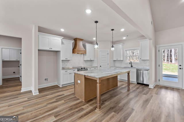 kitchen featuring custom range hood, white cabinetry, stainless steel appliances, and a center island