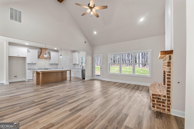 unfurnished living room with ceiling fan, baseboards, visible vents, and light wood-style floors