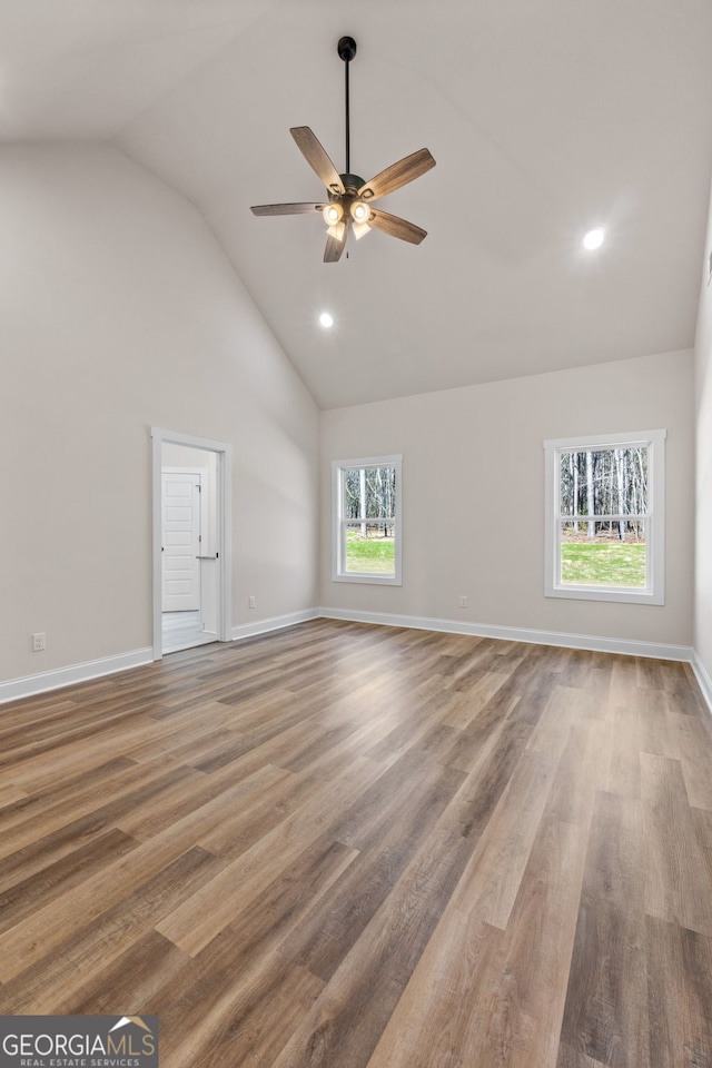 unfurnished living room with ceiling fan, high vaulted ceiling, wood finished floors, and baseboards