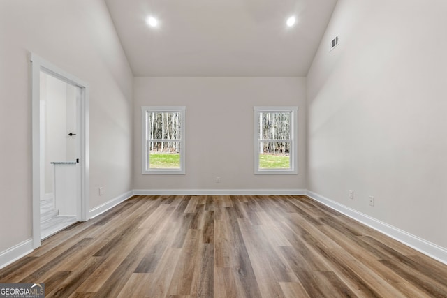 unfurnished room featuring high vaulted ceiling, visible vents, baseboards, and wood finished floors