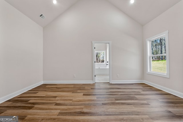 unfurnished room with high vaulted ceiling, recessed lighting, wood finished floors, visible vents, and baseboards