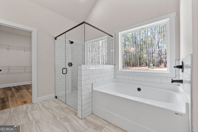 bathroom featuring a stall shower, a walk in closet, and a bath