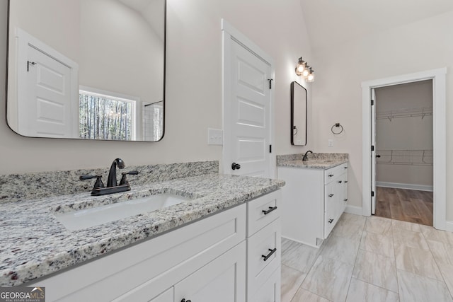 full bath featuring two vanities, a sink, and baseboards