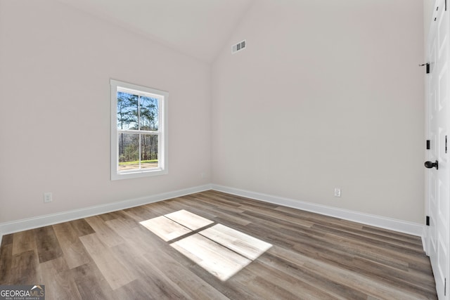 unfurnished room with baseboards, visible vents, vaulted ceiling, and wood finished floors