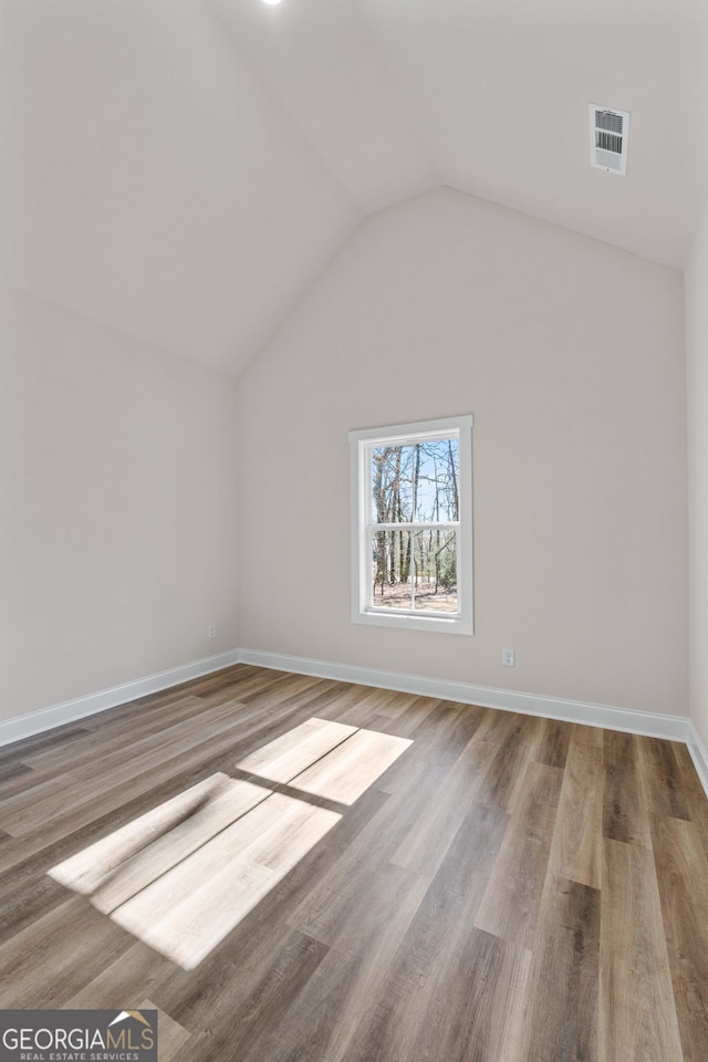 bonus room featuring lofted ceiling, wood finished floors, visible vents, and baseboards